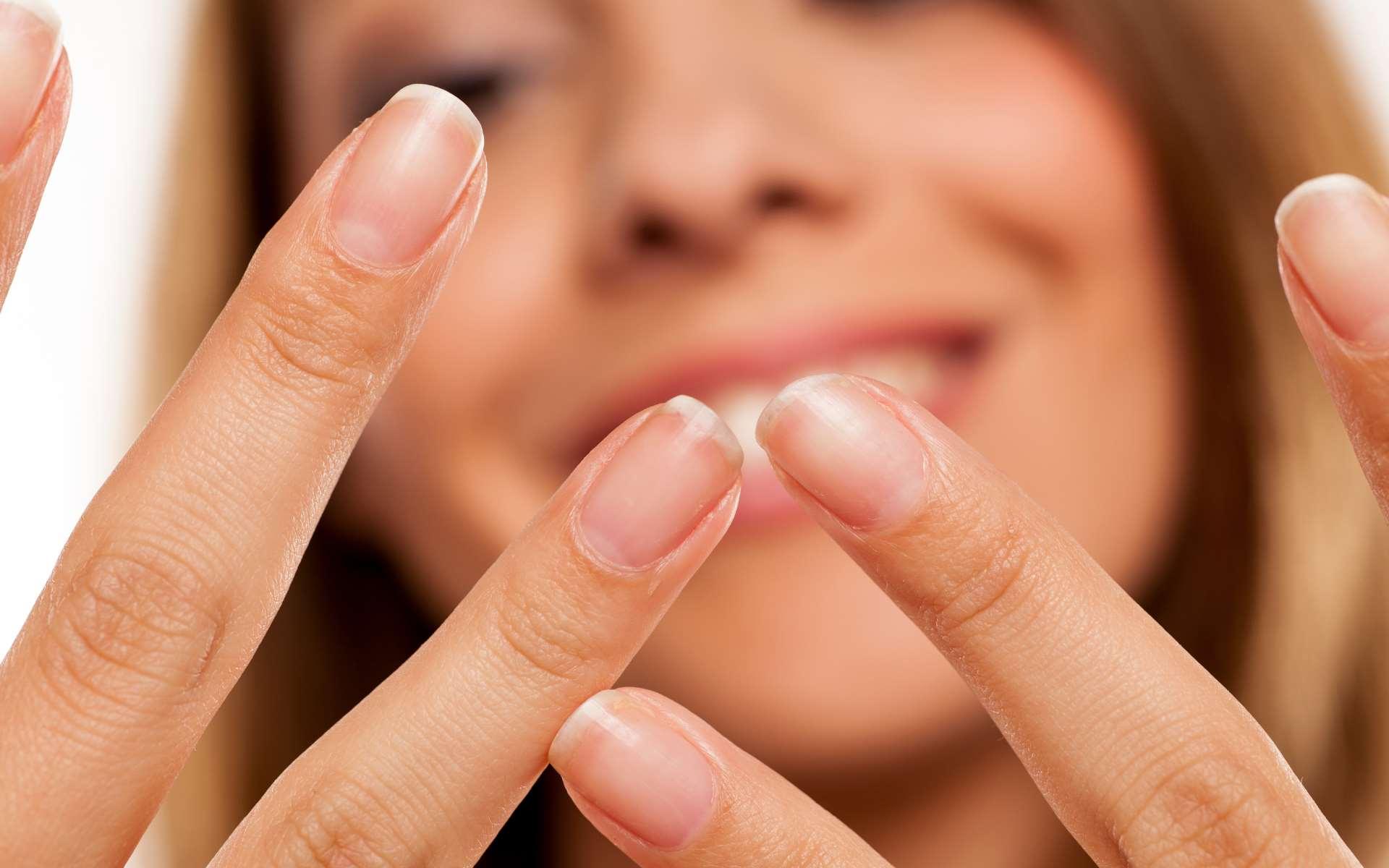 Mains avec beaux ongles au premier plan et visage flouté d'une femme souriante