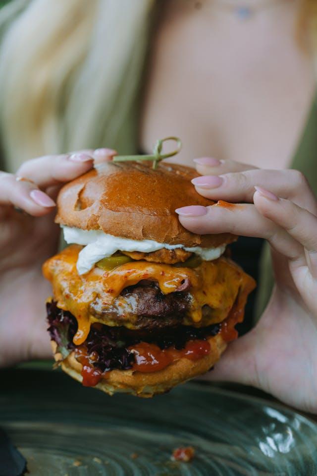 Femme qui tient un hamburger avec sauce et viande