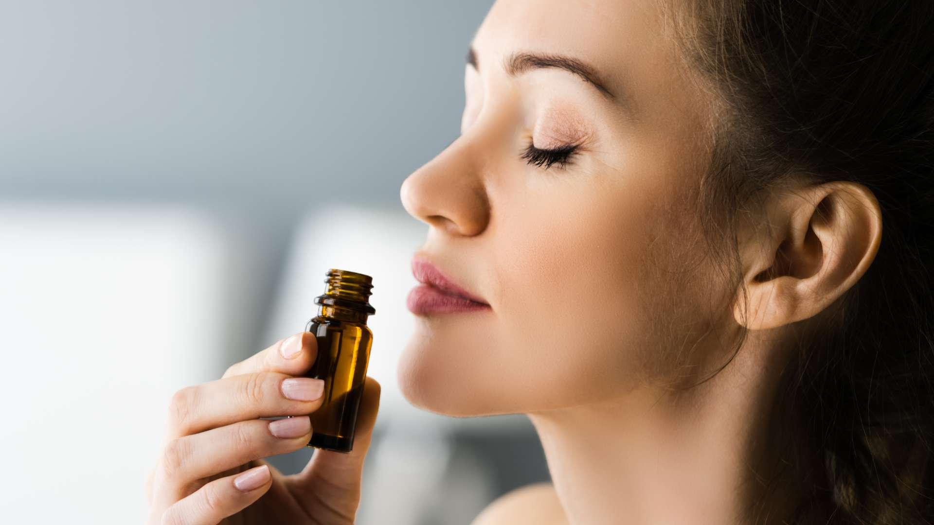 Jeune femme brune de profil qui respire un flacon d'huile essentielle marron