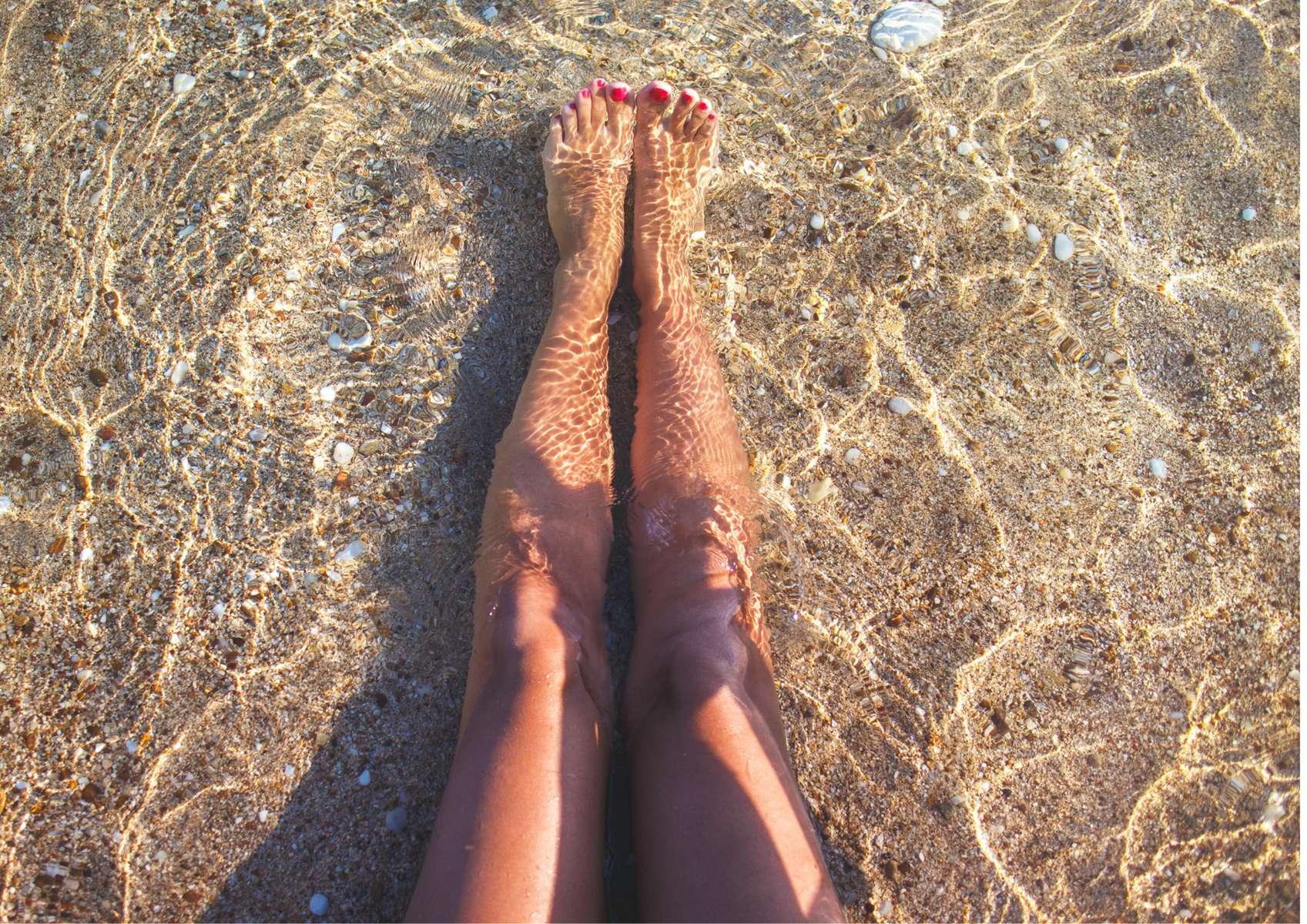 Jambes de femme sur le sable dans la mer