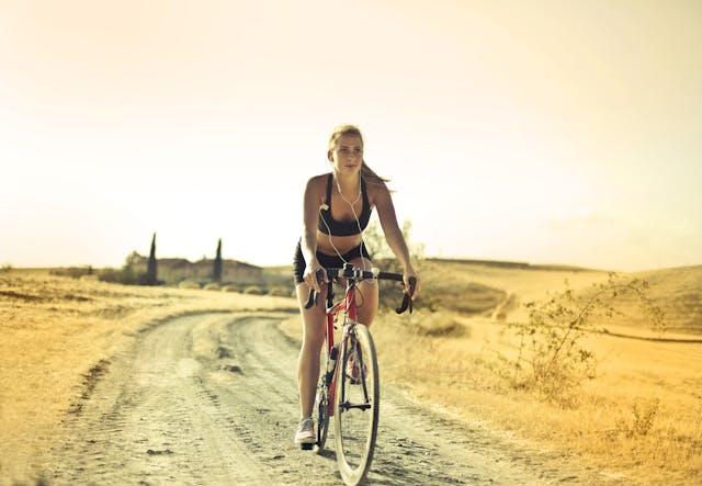 Jeune femme qui fait du vélo sur un chemin de terre 
