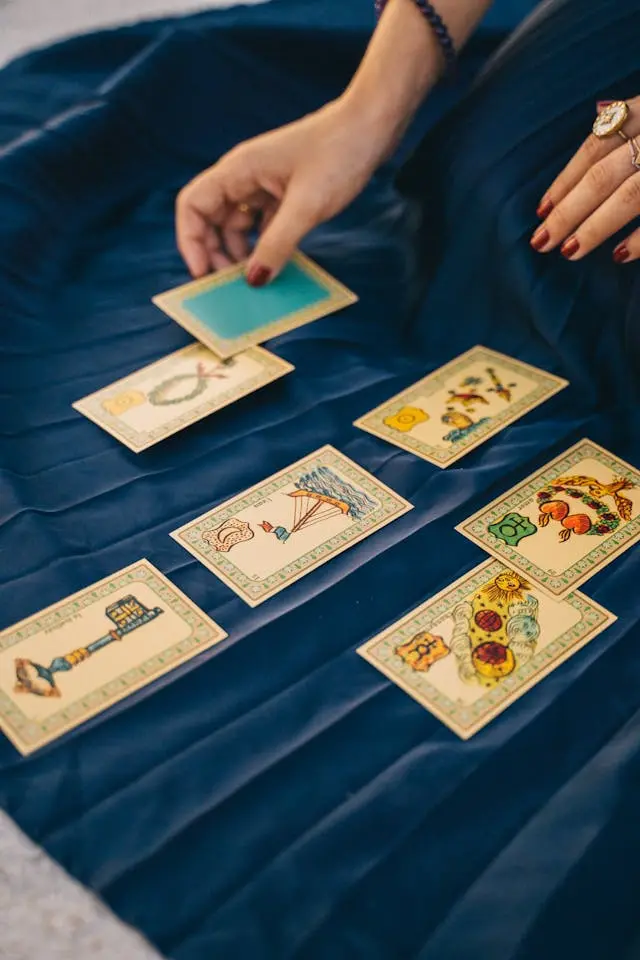 Main de femme qui tient une carte de tarot avec des  cartes sur tissu plissé bleu marine