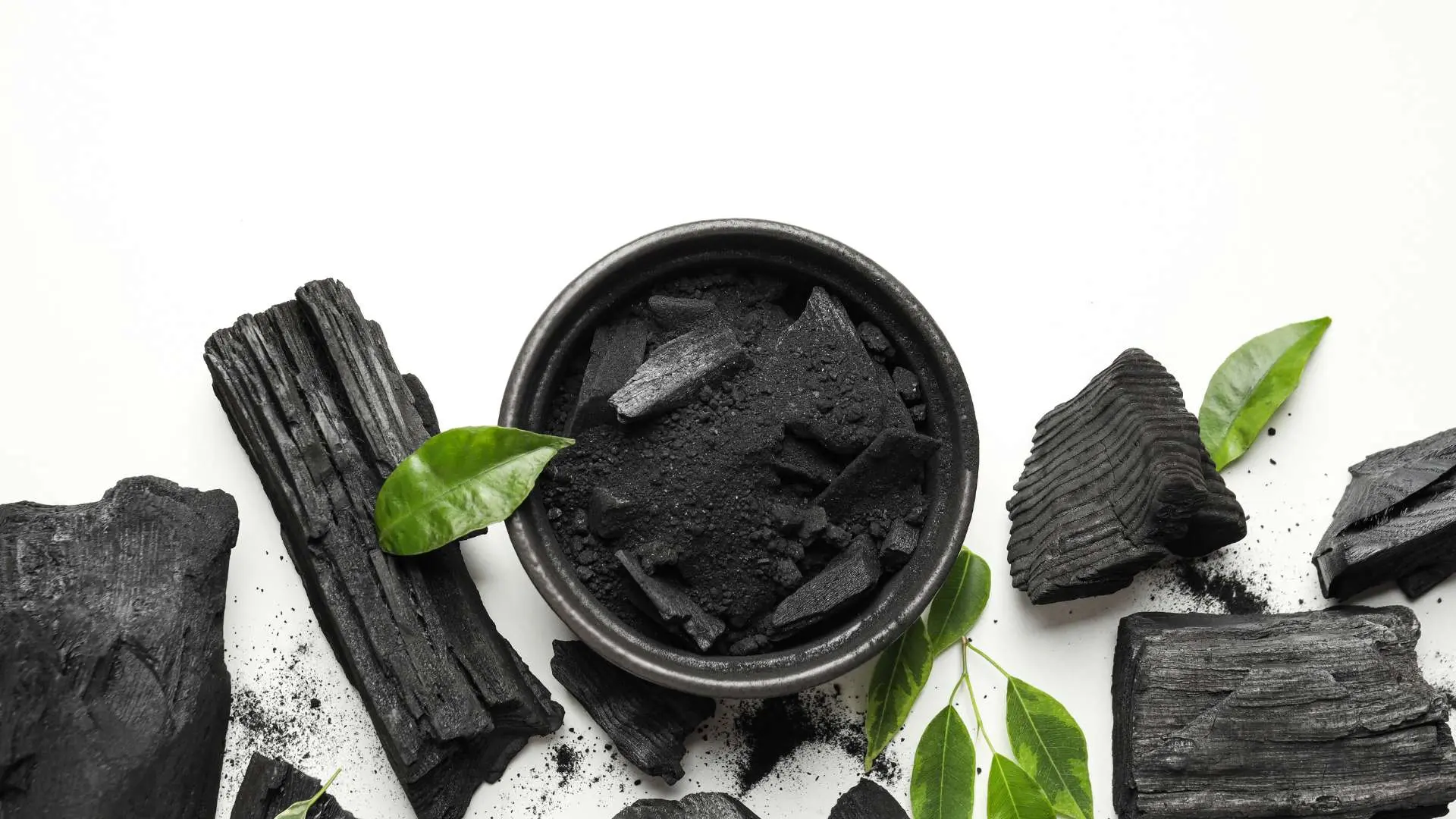 Charbon actif végétal en poudre et solide avec feuilles vertes sur fond b anc