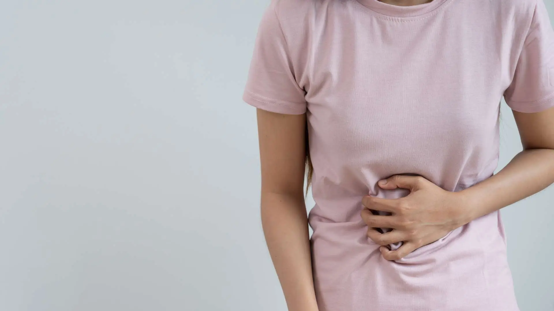 Buste de femme en tee-shirt qui se tient le ventre douloureux