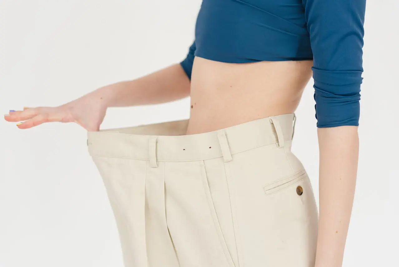 Ventre de femme de profil qui tient son pantalon beige tro pgrand