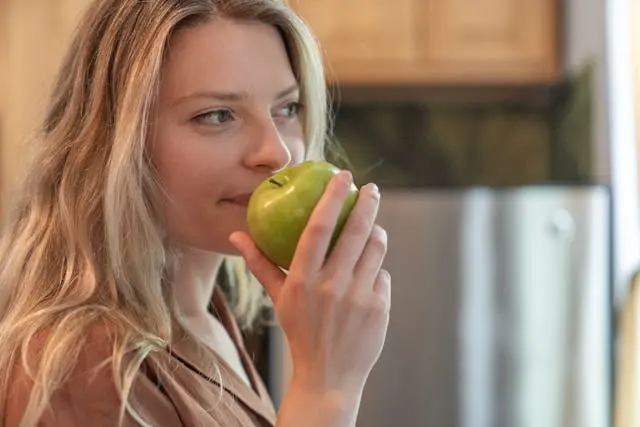 Jeune femme blonde qui tient une pomme verte dans sa main