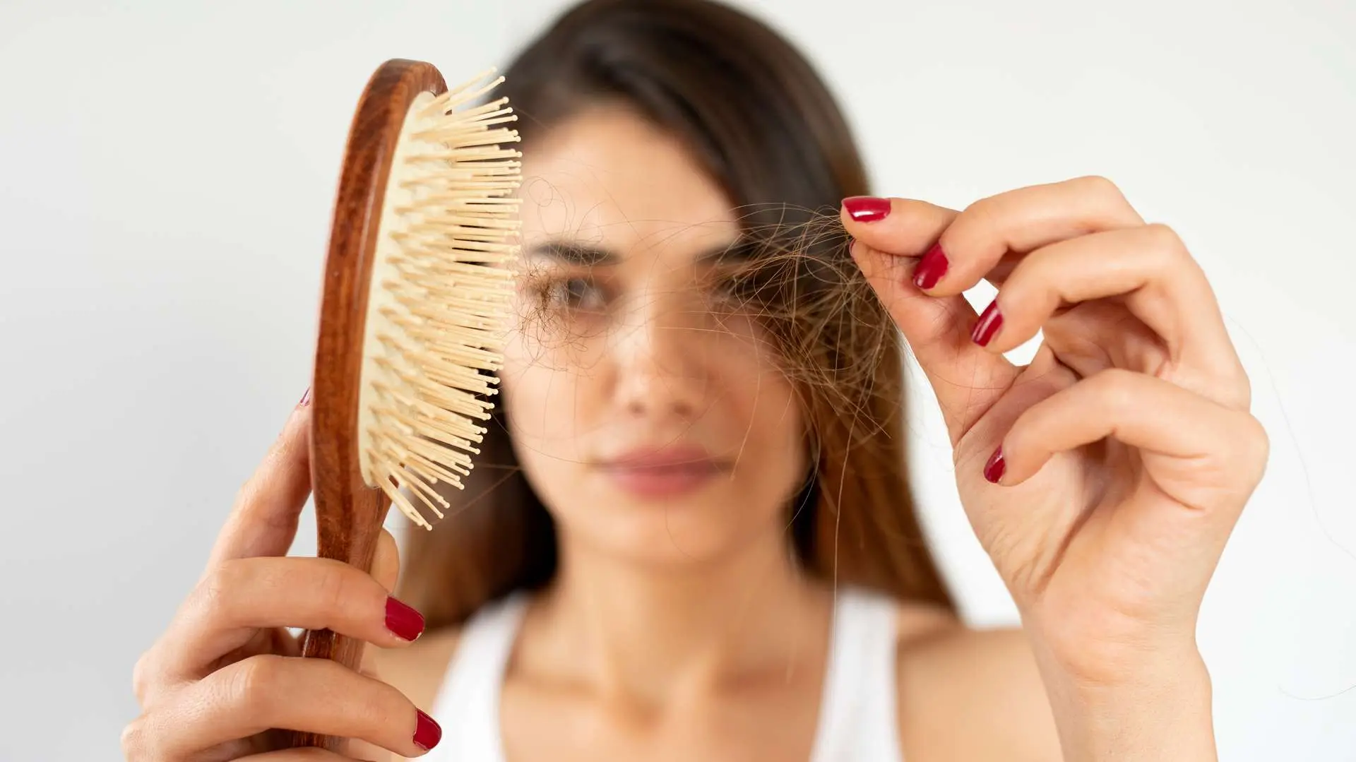 Jeune femme qui tient une brosse d'une main et des cheveux de l'autre