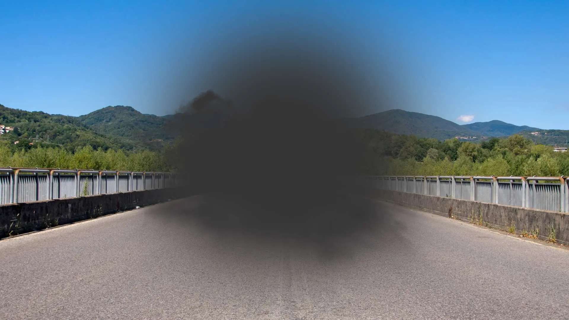 Tache noire qu milieux d'une route avec montagnes en arrière-plan, due à la DMLA