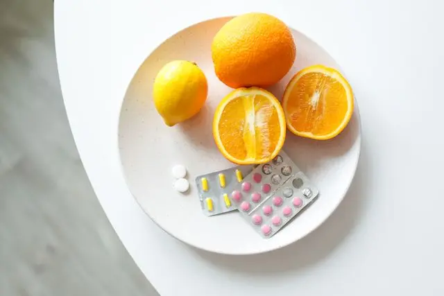 Vue de haut assiette blanche sur une table blanche avec oranges, citrons et compléments alimentaires